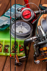 Fototapeta premium Different fishing tacles with lures and reels on wooden brown background with place for text.