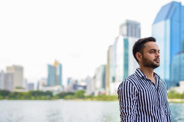 Young bearded Indian businessman relaxing at the park in the cit