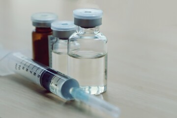 Vaccine vials and syringe on table.