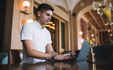 Fototapeta premium Focused man using laptop in restaurant
