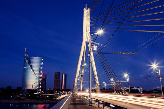 Suspension bridge with skyscrapers on background at night