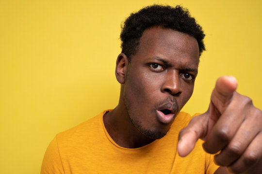 African American Guy In Yellow Casual T-shirt Discovering Hidden Camera. Guy Staring At Camera Attentively.