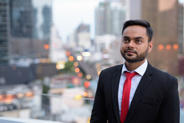 Young bearded Indian businessman against view of the city