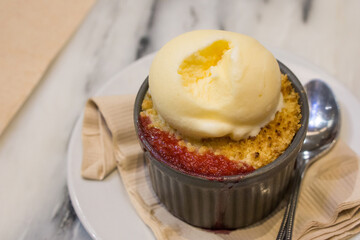 Baked Fruit Crumble with Tahitian Vanilla Ice Cream on the Marble-patterned table.