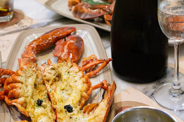 Grilled Lobster with Truffle Sauce, bottle and a glass of sparkling wine on the table.