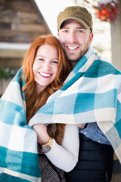 Portrait of mid adult couple wrapped in checked blanket