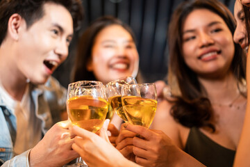 Group of Asian young people hold wine glass and clink glasses in party