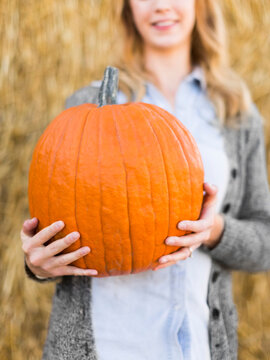 Woman Holding Huge Pumpkin In Pumpkin Patch