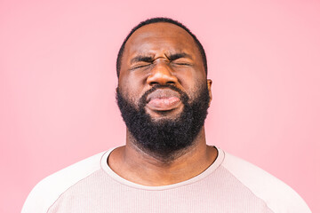 Afro american man isolated against pink background smelling something stinky and disgusting, intolerable smell. Bad smells concept.