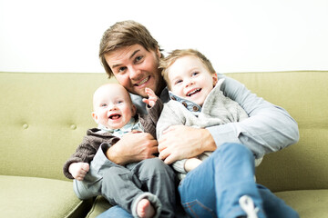 Father embracing two sons (6-11 months and 2-3 years)