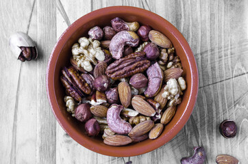 different types of nuts in a brown dish on a black and white background top view