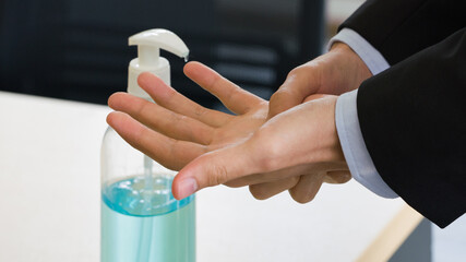 Businessman in black suit washing hands with alcohol gel. Hygiene concept. Prevent the spread of germs and bacteria and avoid infections coronavirus