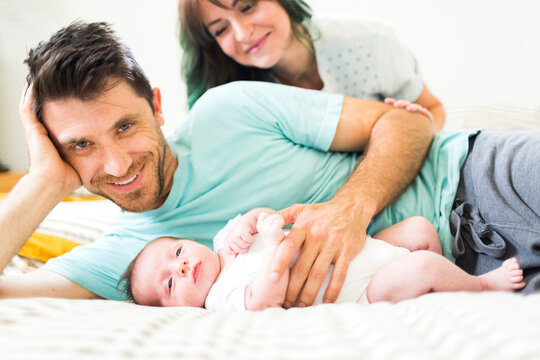 Happy parents with baby boy (6-11 months) lying on bed