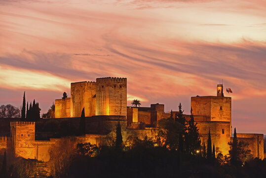 Illuminated castle at dusk, pastel colored clouds in sky
