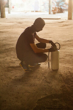 Young graffiti writer with fire extinguisher in dusty old factory.