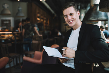 Delighted self employed man with notebook working in cafe