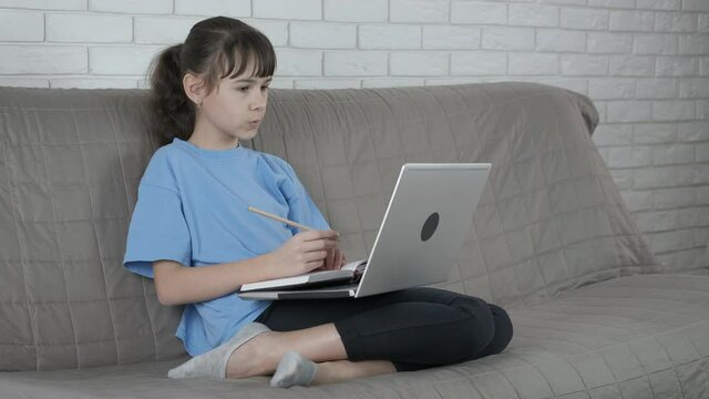 Practice e learning. A little teen sits and listen an internet lesson from home. A concept of e-school from distance.