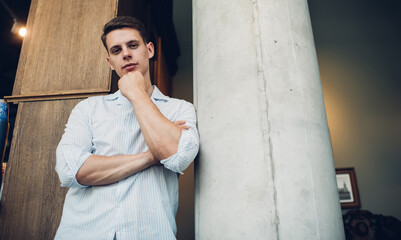 Cheerful man in casual clothes standing near wall