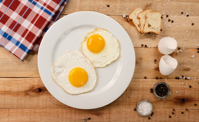 fried eggs, on a white plate, on wooden background. Top Wiew