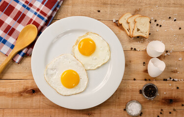 fried eggs, on a white plate, on wooden background. Top Wiew