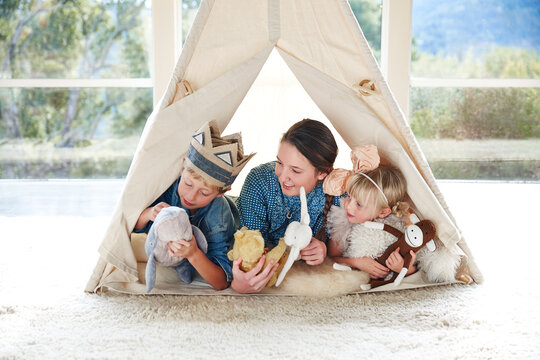 Siblings playing in teepee tent in living room - Powered by Adobe