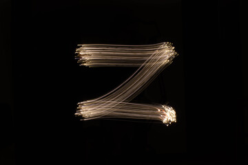Foto de larga exposición de senderos de luz haciendo una forma de letras sobre un fondo negro  con...