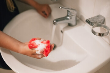 a woman's hand washes the sink with a sponge