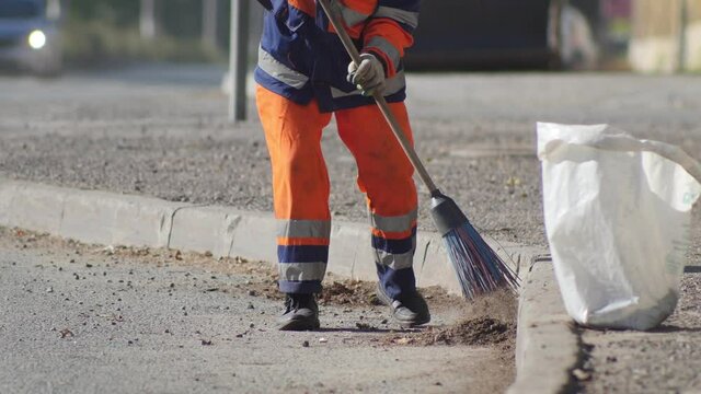 A man cleaning the asphalt with a broom