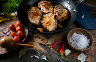 Fried meat in a cast iron pan on a wooden table