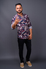 Obraz premium Young bearded Indian man against gray background