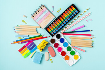 Fototapeta premium Top view of modern bright blue office desktop with school supplies on table. Back to school concept