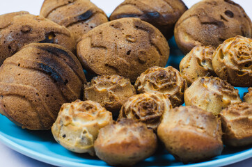 Cupcakes of different shapes on a blue plate close-up.