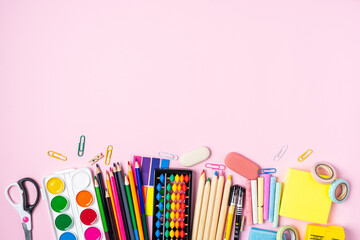 Flat lay of modern pink office desktop with school supplies on table around empty space for text. Top view Back to school concept. Copy space.