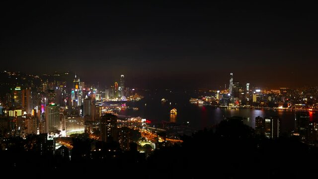 Hong Kong and Victoria Harbour at night, panoramic view from top of island hill. Lights of the city and dark water in middle, scenic perspective of Asian metropolis