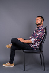 Young bearded Indian man against gray background