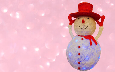 Figure of a cheerful snowman in a red hat and mittens, on a light bokeh background. Free space for...