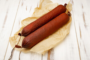 Two sticks of sausage on a light wooden background. Natural sausage.