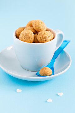 group of amaretti in a blue cup with spoon on blue background