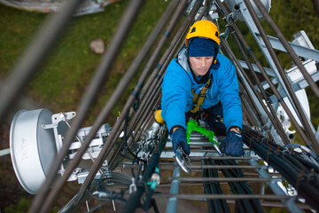 Working at heights, technician climbs up on a communications tower