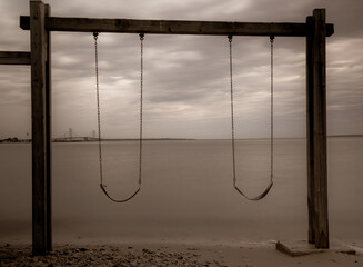 Cloudy Lake Huron and swing on the beach at dawn in summer Michigan