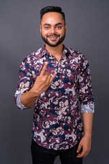 Young bearded Indian man against gray background