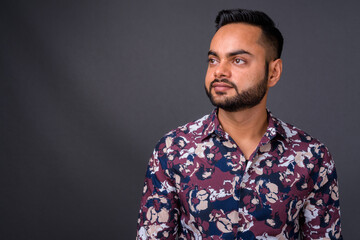 Young bearded Indian man against gray background