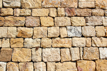 horizontal background of rows of old wall blocks in summer in the sun with relief and texture