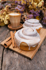 Soft focus Cinnamon Rolls in a wooden plate and coffee latte on a wooden table and flower background