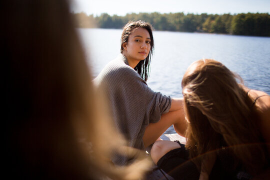 A group of friends are hanging on the dock during a summer afternoon