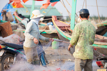 Fishermen repairing nets on a boat trip out to sea in the afternoon July 31, 2016 at the beach of...