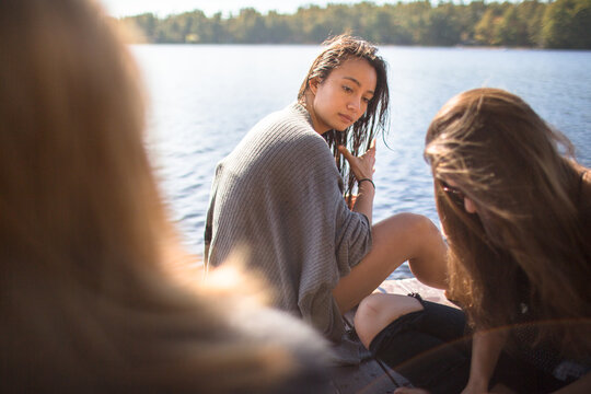 A group of friends are hanging on the dock during a summer afternoon