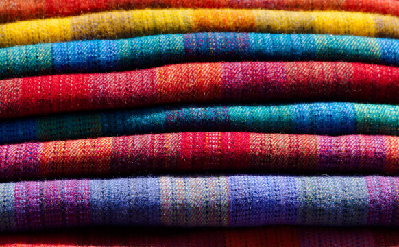 Abstract shot of colourful blankets folded on top of each other.
