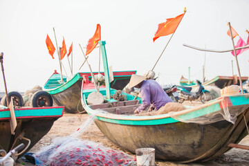 Fototapeta na wymiar Fishermen repairing nets on a boat trip out to sea in the afternoon July 31, 2016 at the beach of Hai Ly, Vietnam.