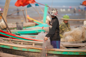 Fishermen repairing nets on a boat trip out to sea in the afternoon July 31, 2016 at the beach of...